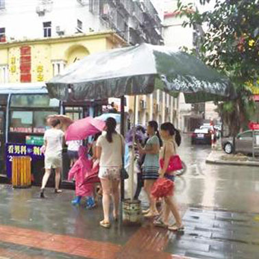 爱心大雨伞传递正能量 超市老板公交站撑雨伞